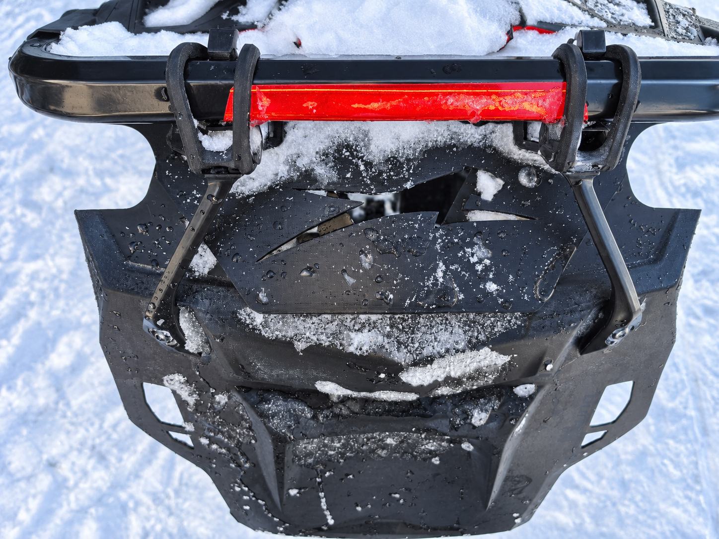 Close view of the development adapter and snowflap mounting assembly with snow and water droplets
